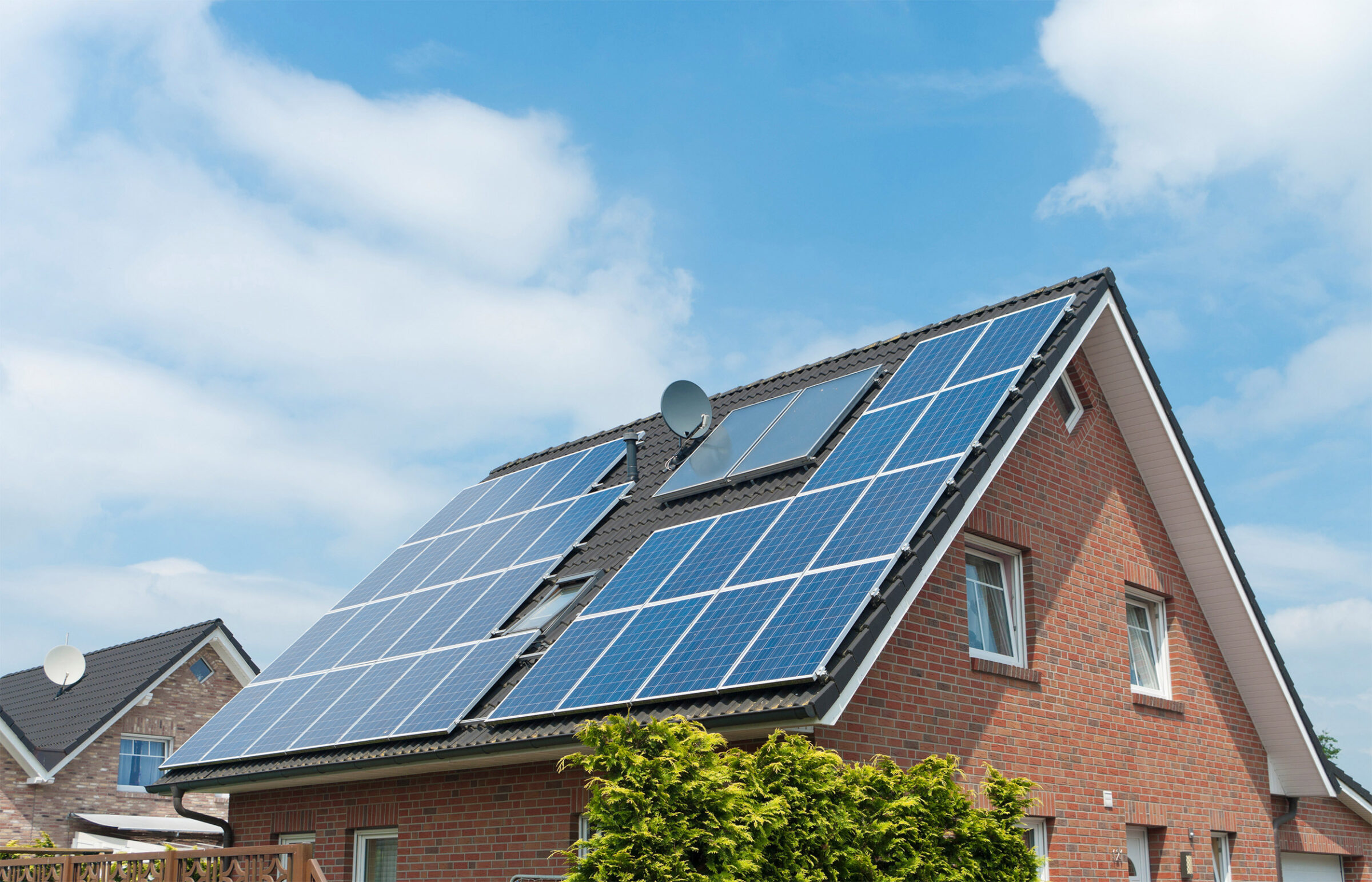 Solarpflicht: Einfamilienhaus mit Solarpaneelen auf dem Dach vor blauem Himmel.